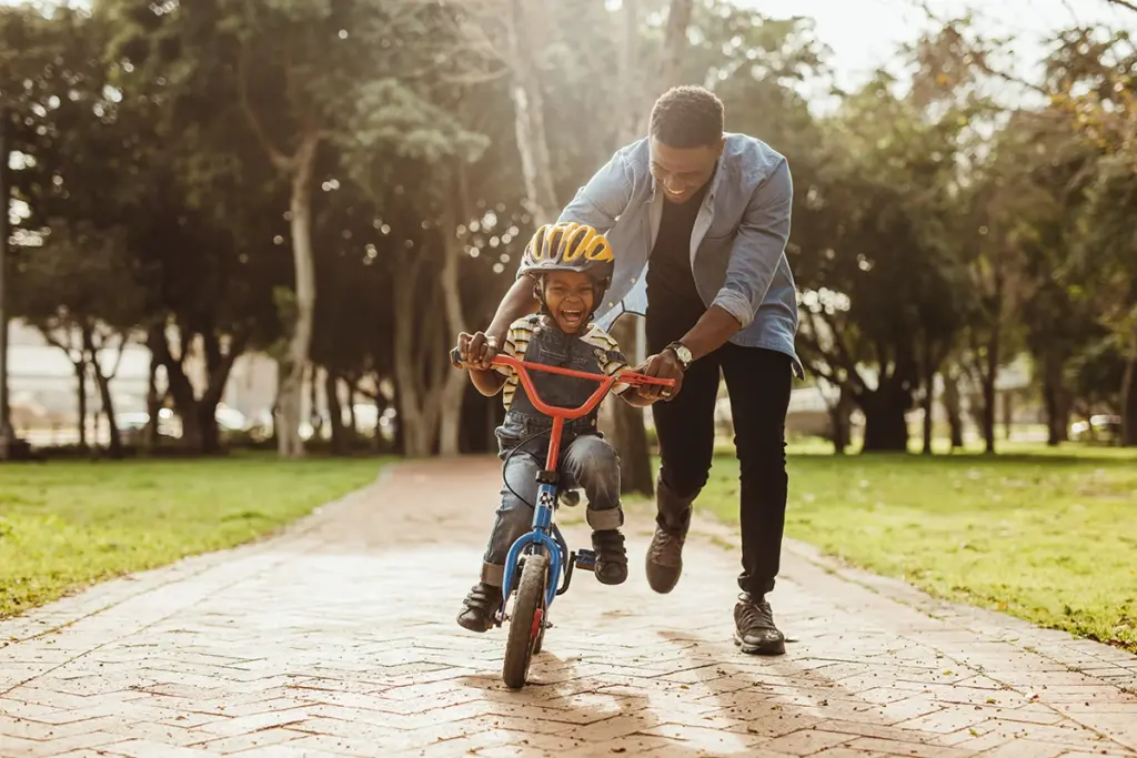 young boy learning to ride bike with father